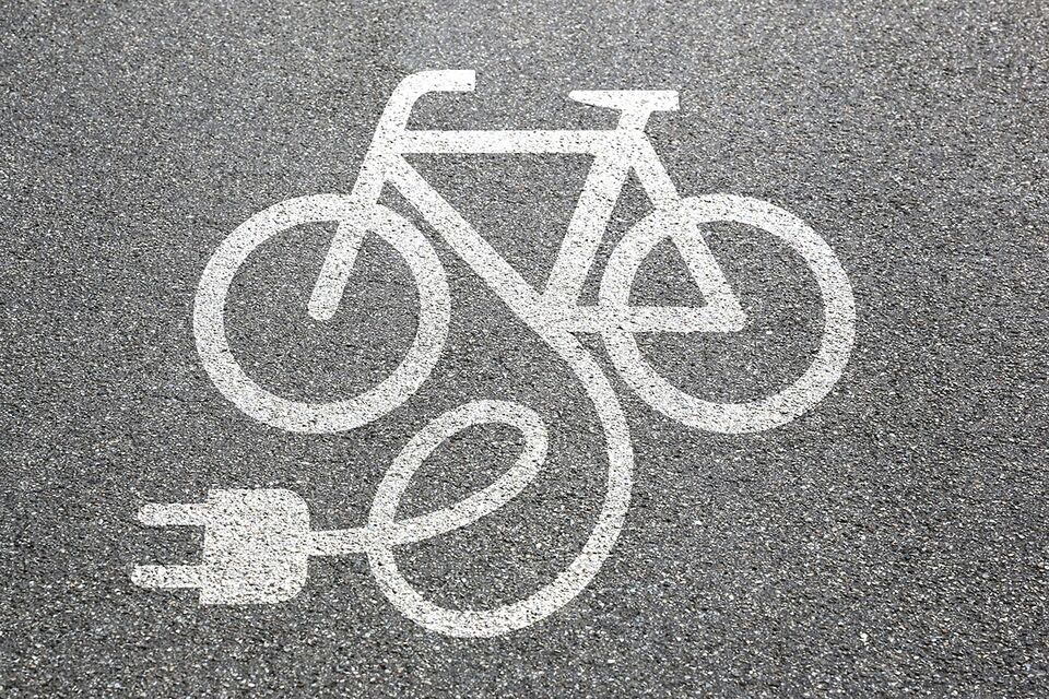 Grafik weißes Fahrrad mit Stecker dran auf Asphalt