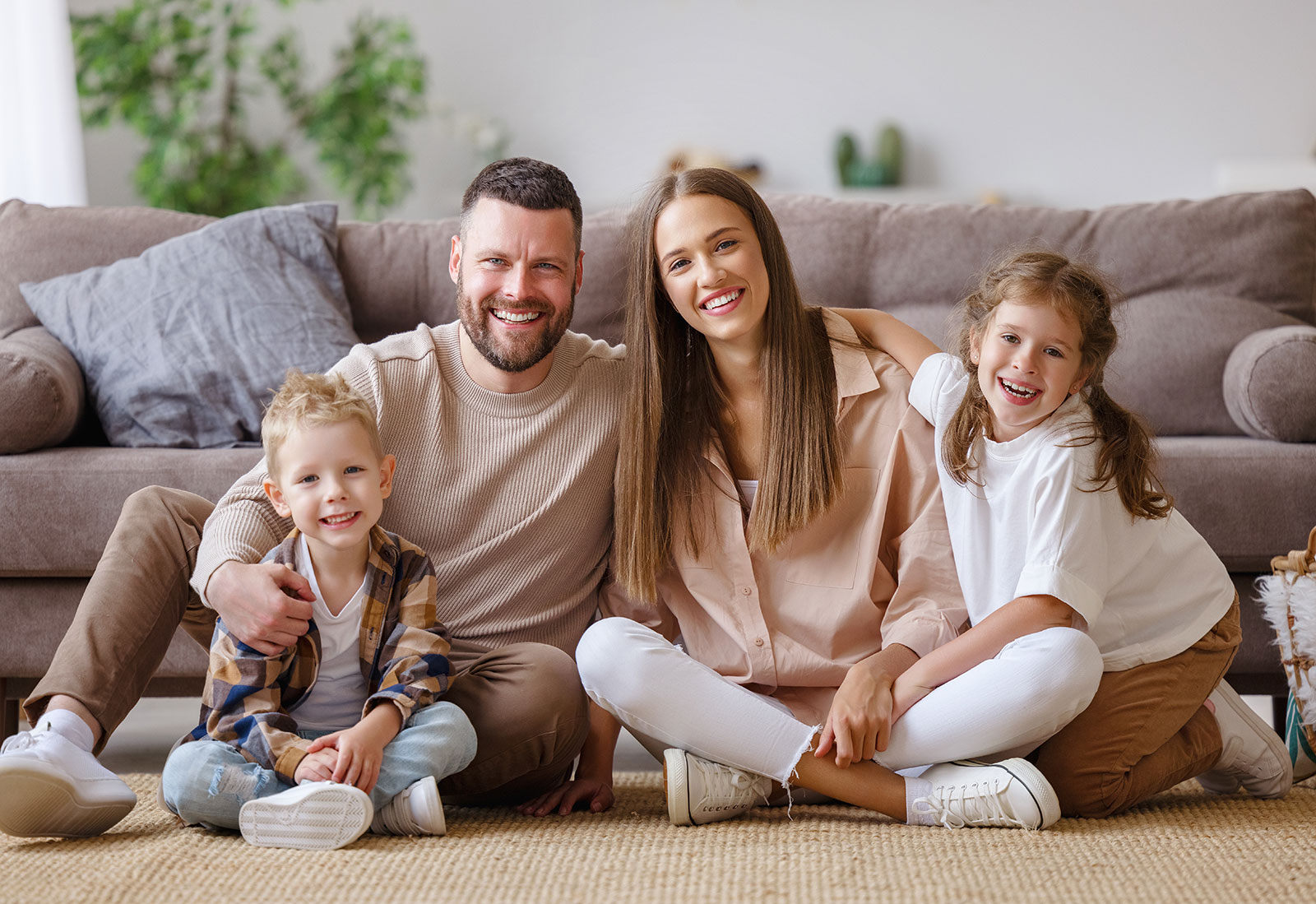 Vater, Mutter und die zwei Kinder sitzen auf dem Boden vor der Couch