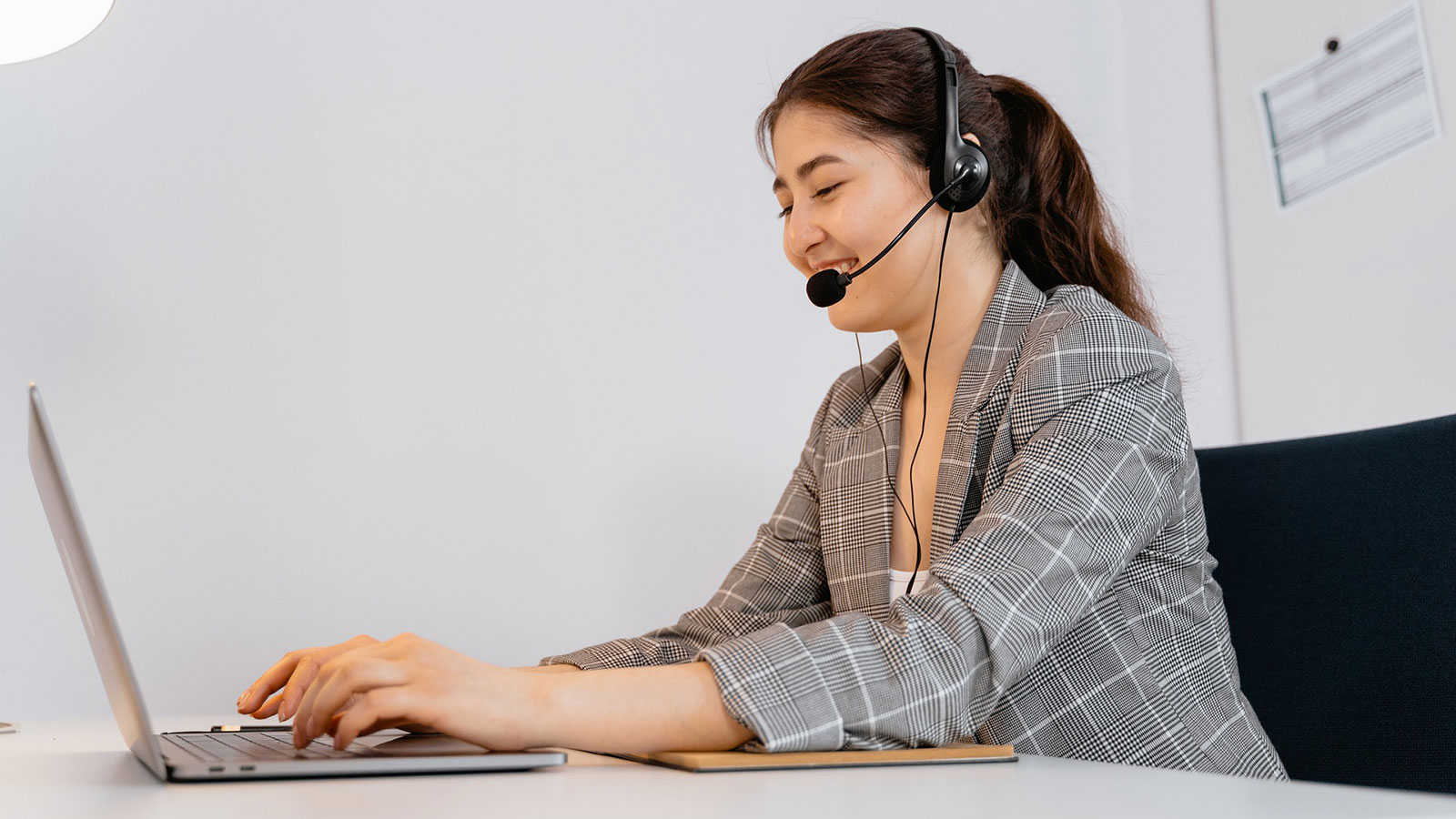 Frau mit Headset sitzt am Laptop