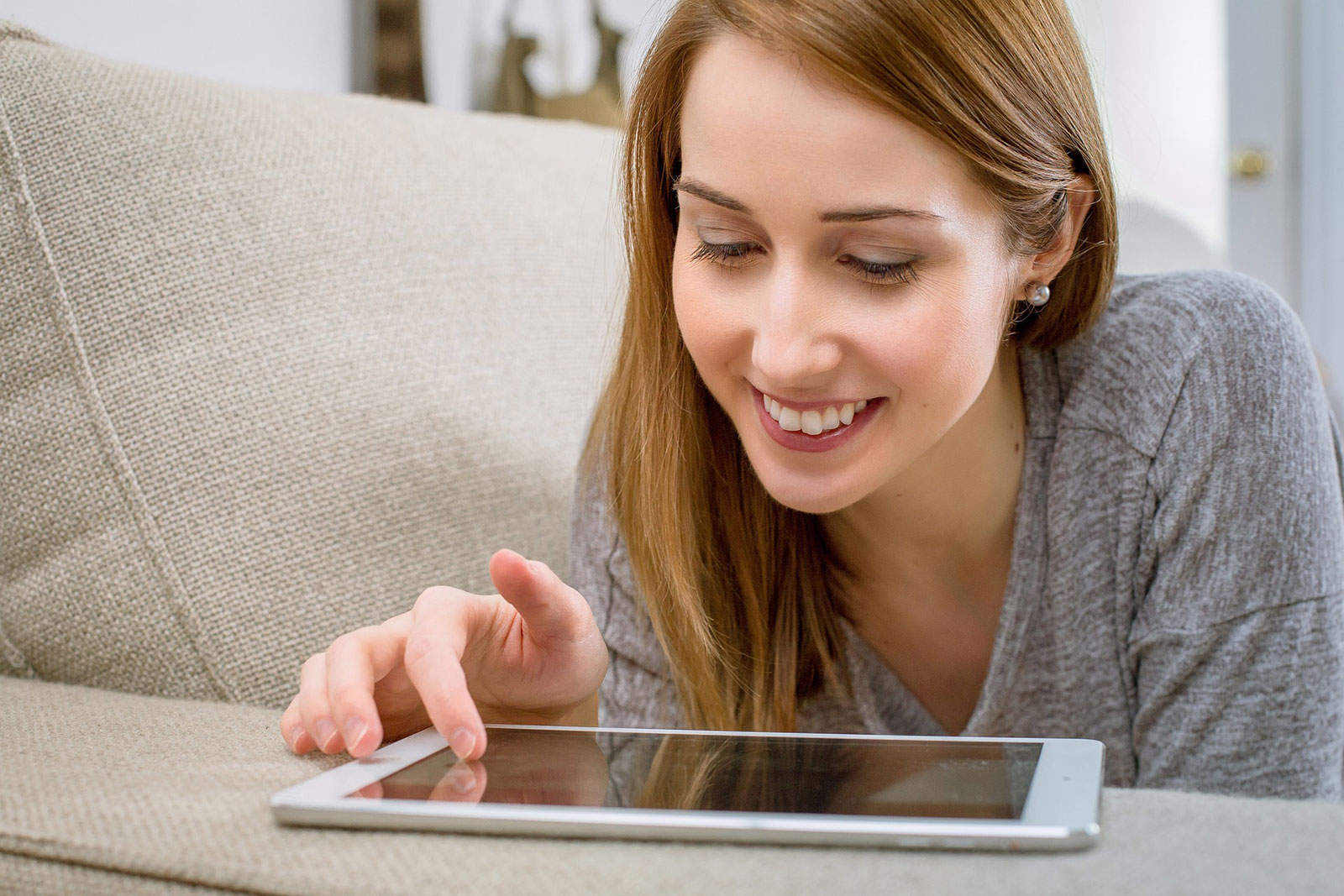 Bankverbindung per Onlineformular ändern (Bild: © Martine – Pixabay) Frau liegt auf der Couch, bedient Tablet